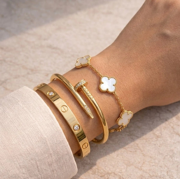 Woman wearing a 3 piece anti-tarnish gold plated bracelet stack combo featuring screw, nail, and white clover designs