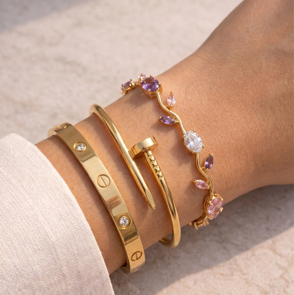 Model wearing a 3-piece anti-tarnish gold plated bracelet stack including a nail bangle, screw bangle, and gem vine bracelet.