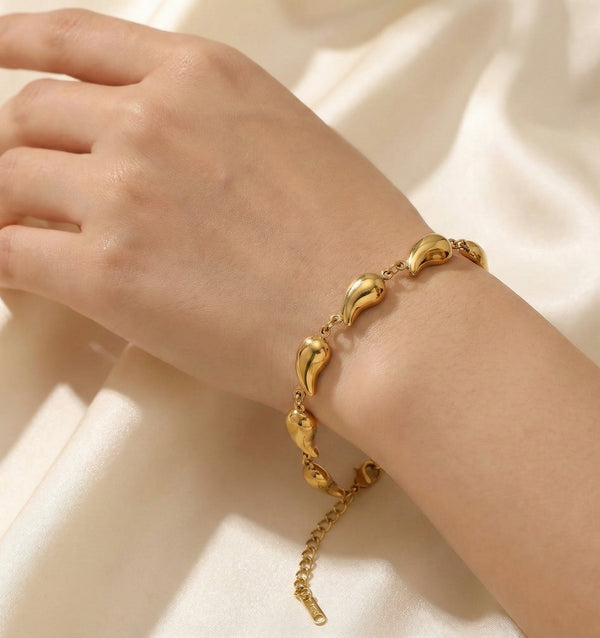 Aesthetic flat lay showing the smooth waterdrop links of the gold-plated bracelet