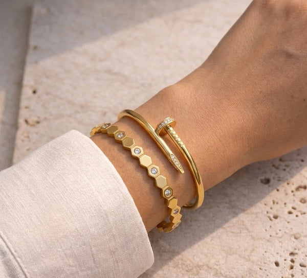 Aesthetic nail and hexagon bracelet stack worn on wrist in sunlight.