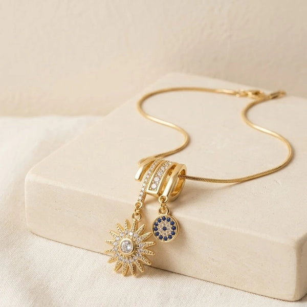 Anti-tarnish gold plated evil eye and sunburst pendant necklace on a sleek snake chain.
