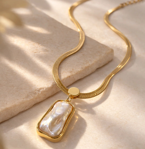 Front view of anti-tarnish gold plated baroque pearl pendant necklace on a flat surface