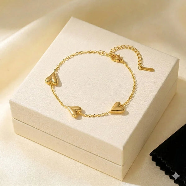 Anti-tarnish gold plated triple heart charm bracelet on a neutral background