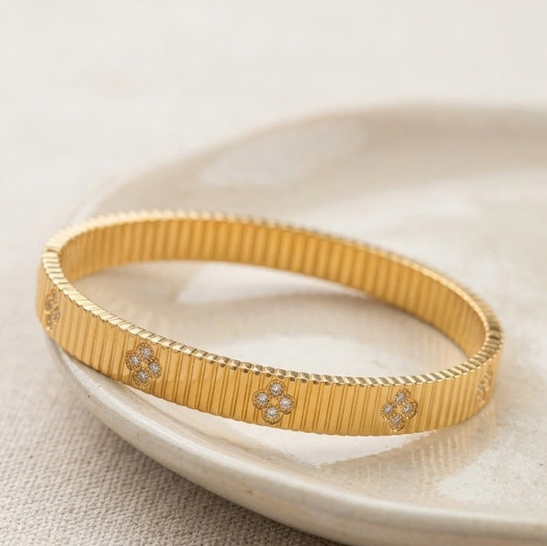 Close up details of ribbed texture and sparkling clover accents on gold-plated cuff