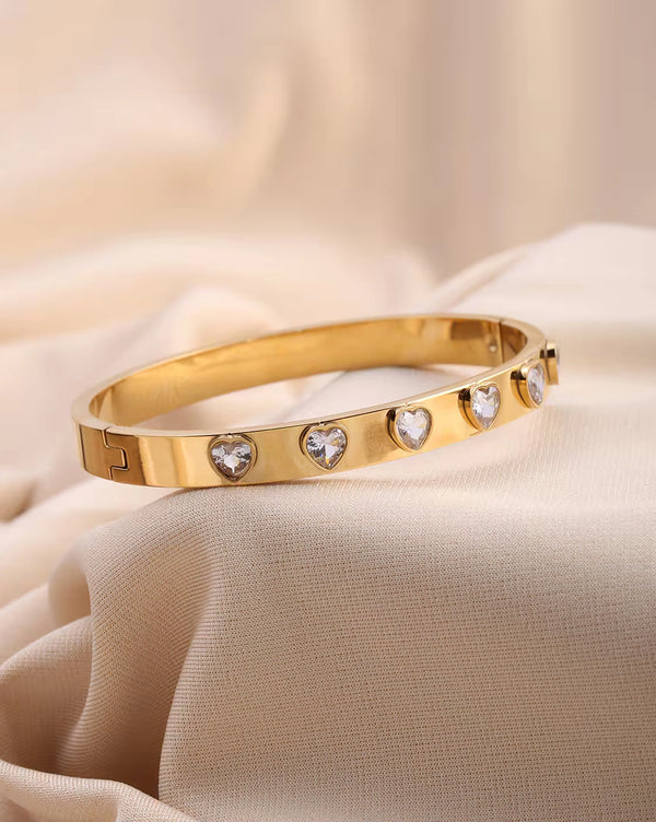 Close up details of sparkling heart CZ stones on gold plated bangle