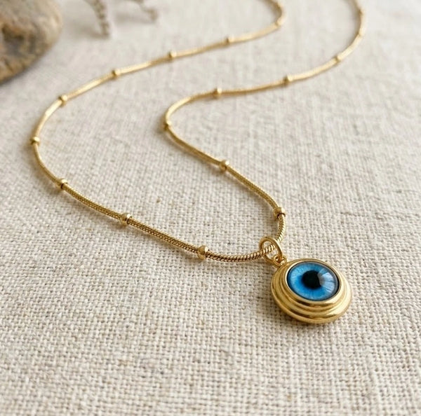 Close up of dainty evil eye pendant on beaded chain