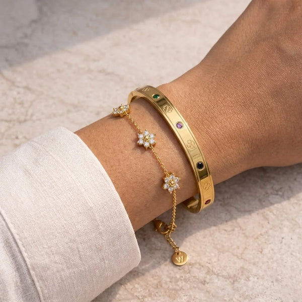 Model wearing aesthetic anti-tarnish gold plated daisy charm chain and gemstone bangle bracelet stack on wrist.