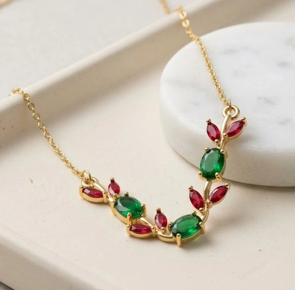 Close up detailing of green oval and red marquise stones in a floral vine motif