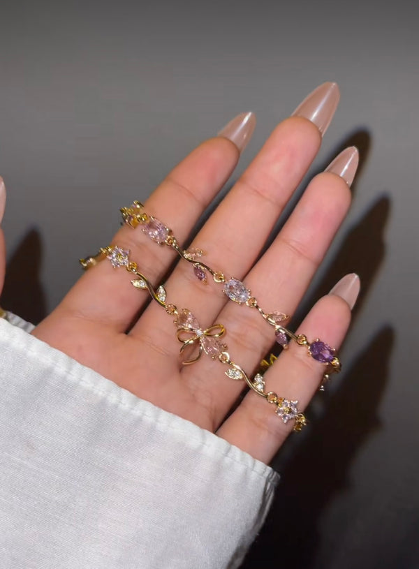 Anti-tarnish gold floral and bow bracelet set on hand in sunlight