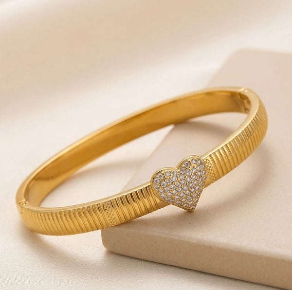 Front view of gold plated ribbed bangle with sparkling rhinestone heart
