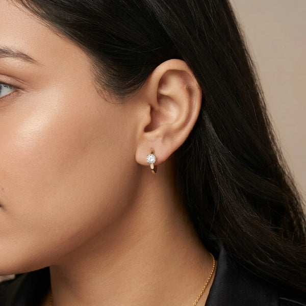 Close up of small gold plated hoop earrings featuring a single cubic zirconia stone