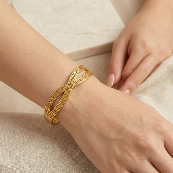 Front view of Greek Key crossover gold-plated bracelet on woman's wrist