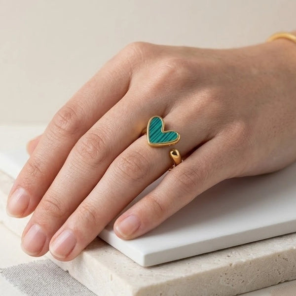 Close up of a woman wearing a high quality gold adjustable ring with a green striped heart stone