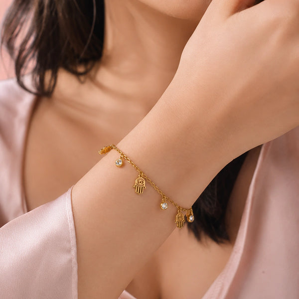 Close up of hand charms and lobster clasp on a gold-plated minimalist bracelet