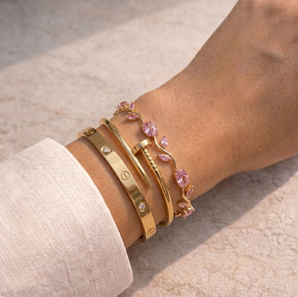 Model wearing a 3-piece gold plated IT-Girl bracelet stack featuring pink stones and minimalist bangles
