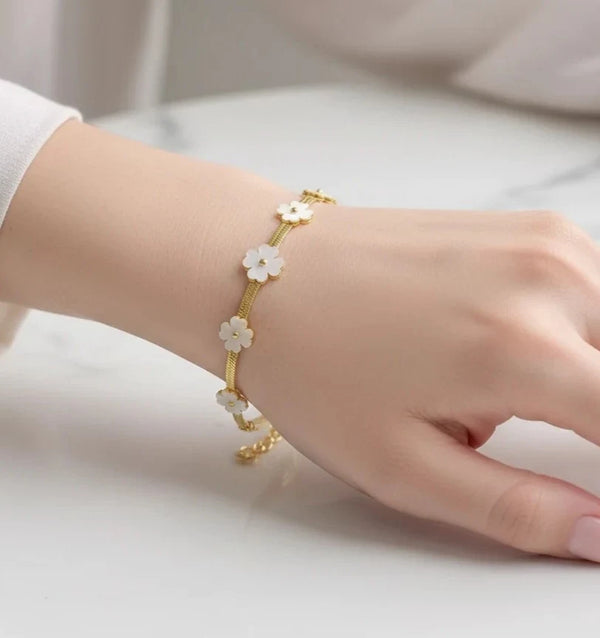 Minimalist gold snake chain bracelet with white enamel flower design for women.