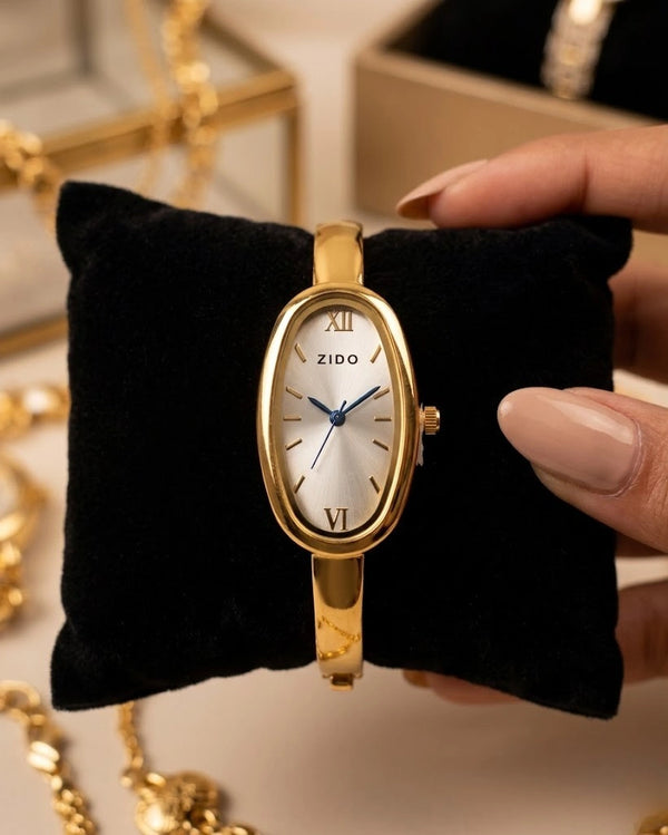 Elegant oval watch with a cream dial and anti-tarnish gold plated finish worn on a wrist.