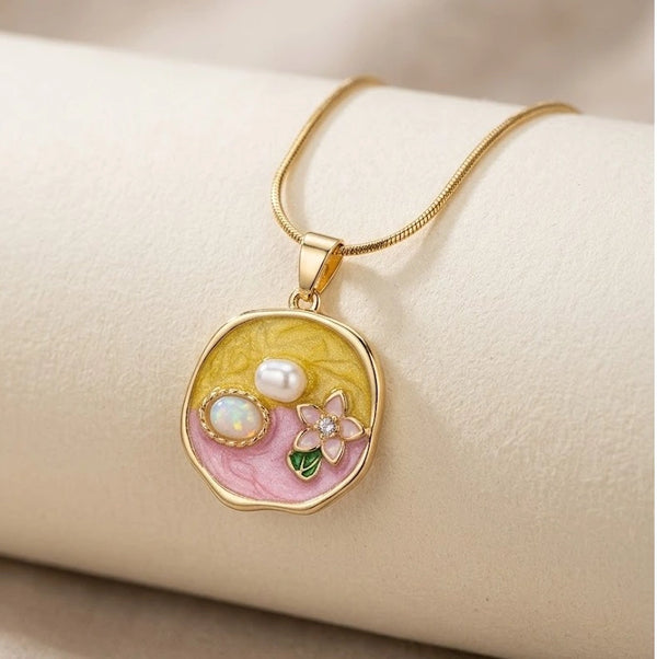 Close up of pastel dual tone pendant featuring faux pearls on a delicate snake chain