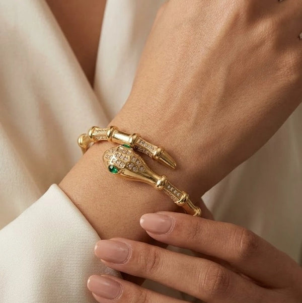 Front view of serpent wrap anti tarnish gold plated bracelet with green eyes