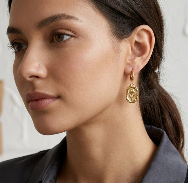 Close up detail of the embossed tulip flower design on the gold plated earring pendant