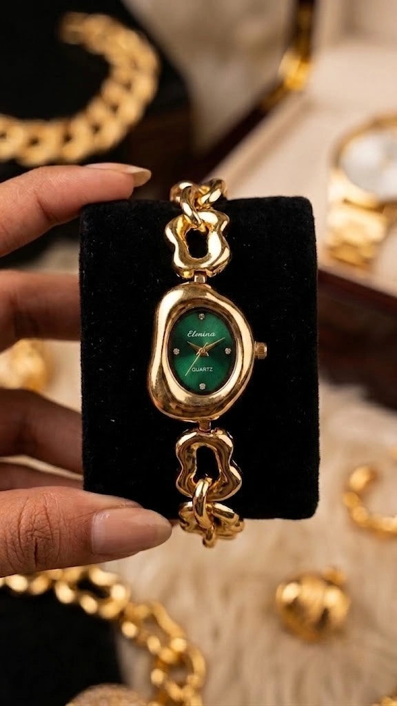 A close-up of the women's watch featuring an emerald green dial and molten gold-plated case resting on a black display cushion.