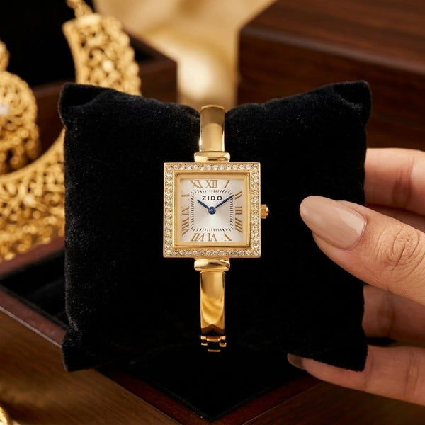 Front view of the vintage square dial watch in an anti-tarnish gold-plated finish resting on a black velvet display cushion.